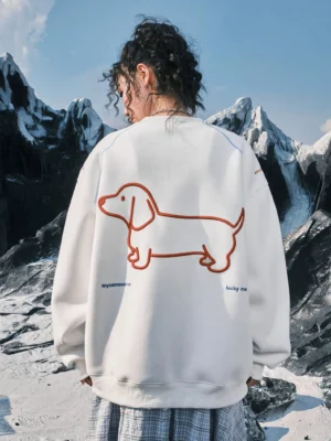 White oversized dachshund embroidered sweatshirt shown from the back with large red dog embroidery and contrast seams in an outdoor mountain setting