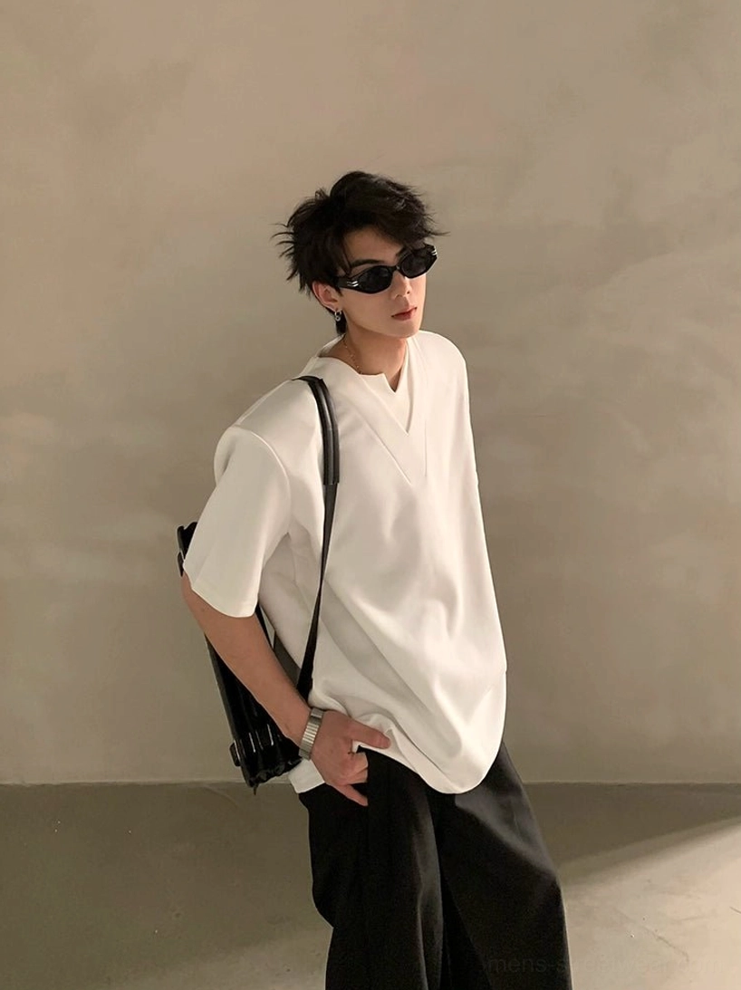 White deep V notched neck streetwear shirt shown from the rear side with black wide leg pants and a shoulder backpack