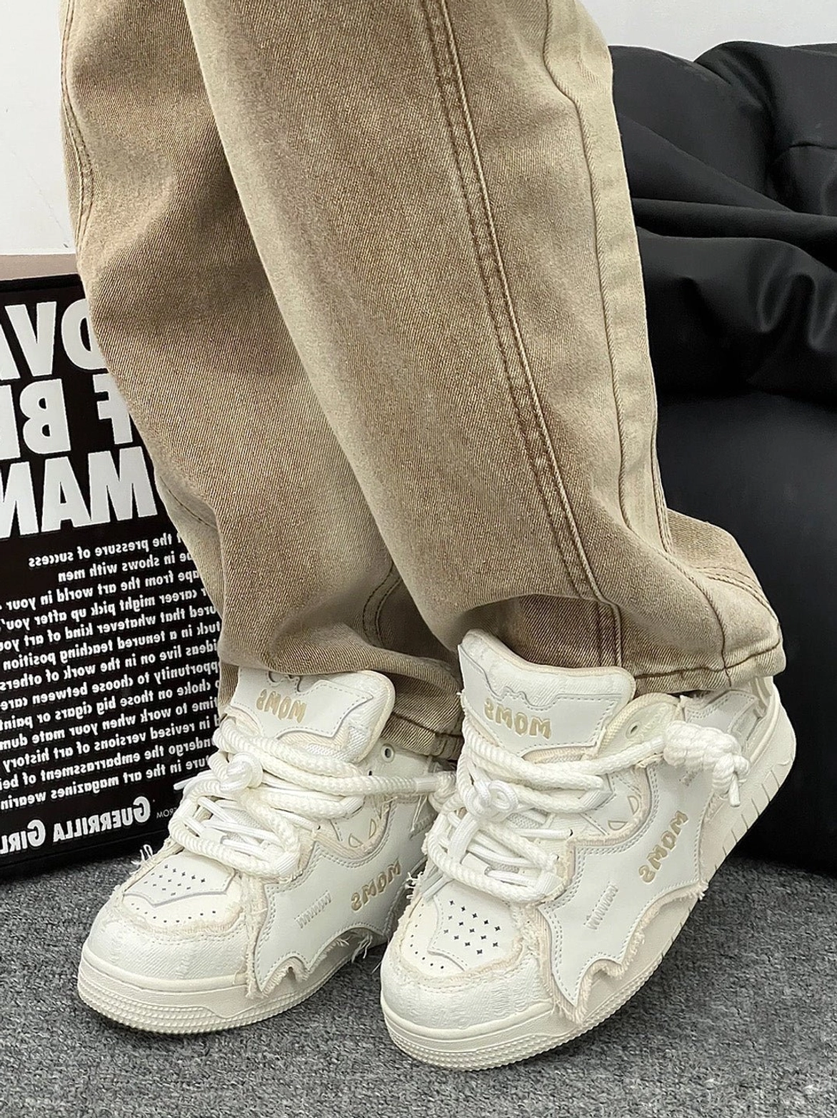 White distressed platform skate sneakers worn with khaki straight-leg jeans, showing the chunky rear sole, bat-inspired side panels, textured laces, and retro streetwear construction
