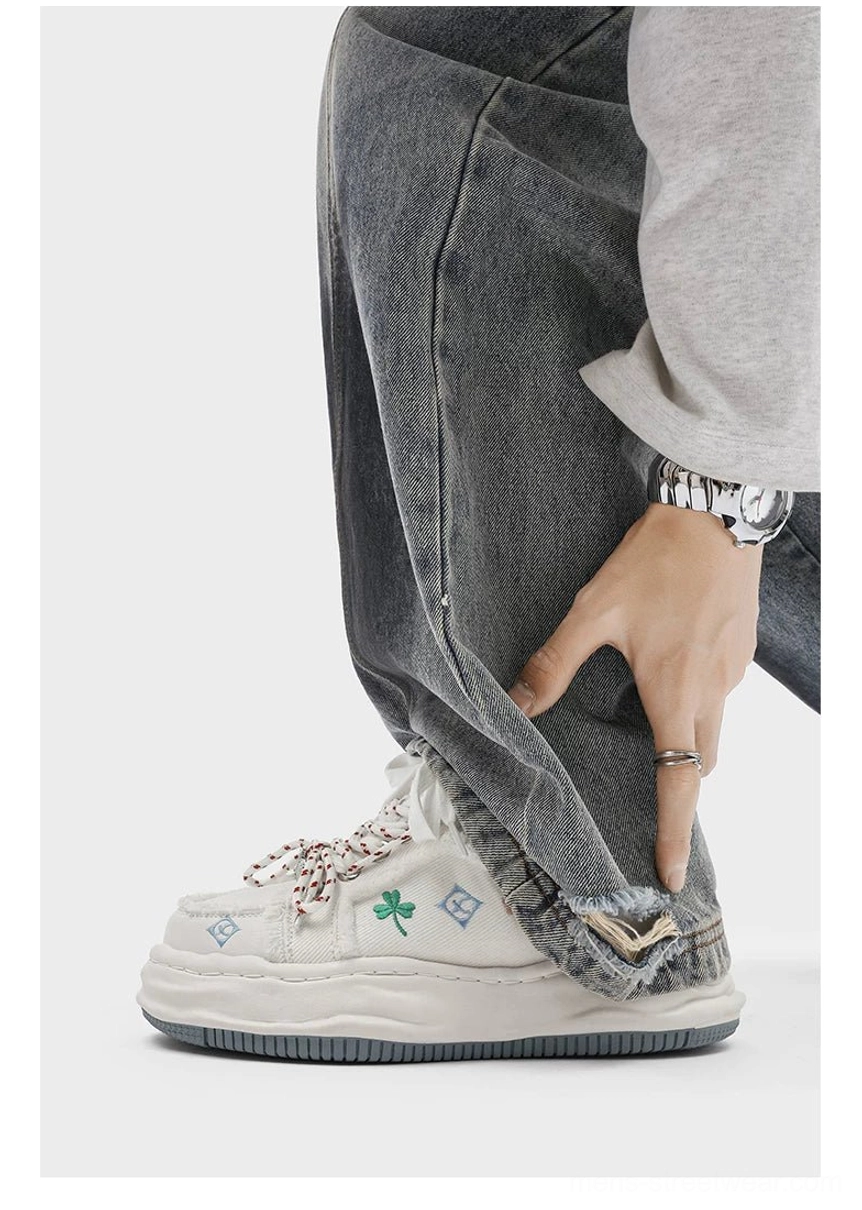 White distressed embroidered platform sneaker worn with rolled denim in a low angle casual streetwear outfit