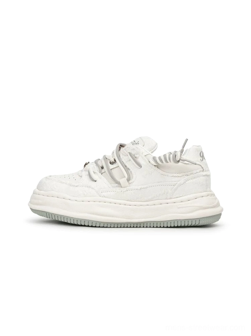 White distressed low-top platform sneaker displayed in a clean side profile with matte worn upper and sculpted dissolved-style thick sole