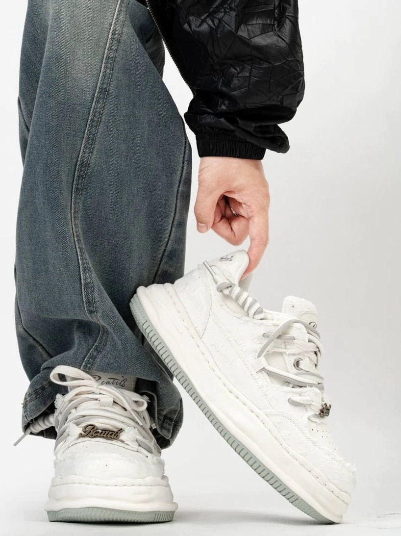 Side view of white distressed mixed-material low-top platform sneaker with layered upper, gray rubber outsole, and heel tab