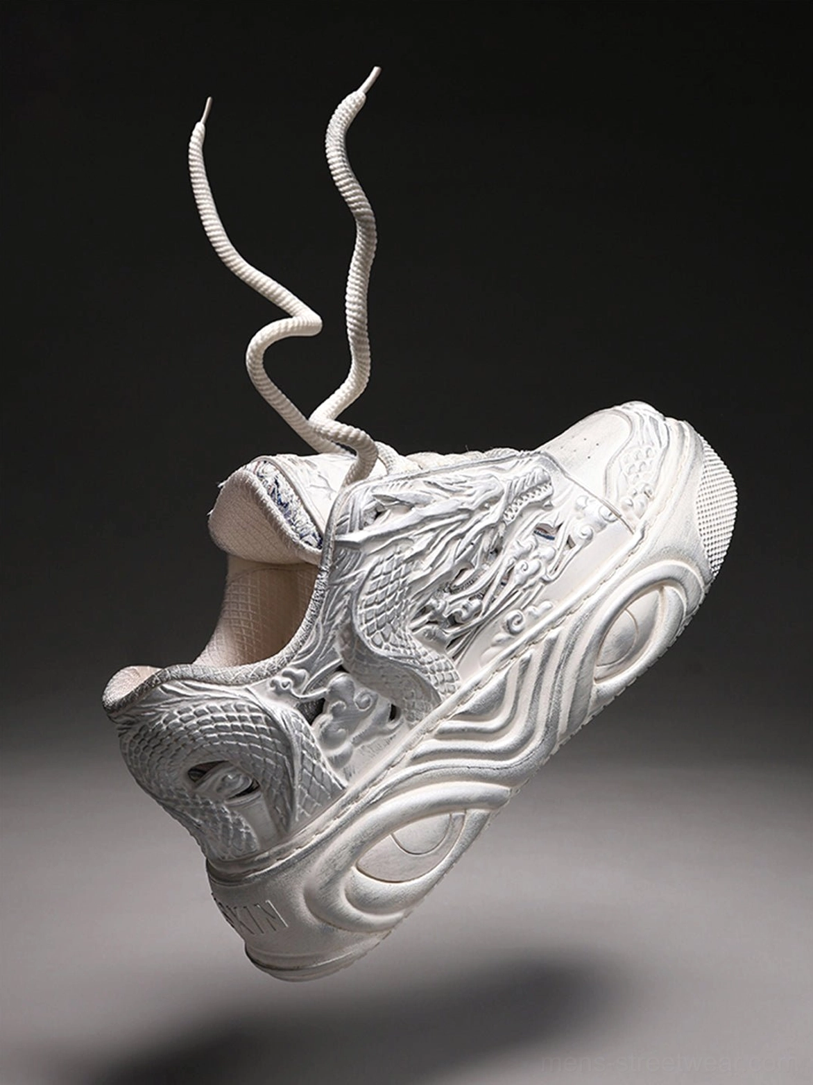 Dragon relief platform sneaker floating in a dark artistic studio with sculpted embossed details and a chunky wavy sole