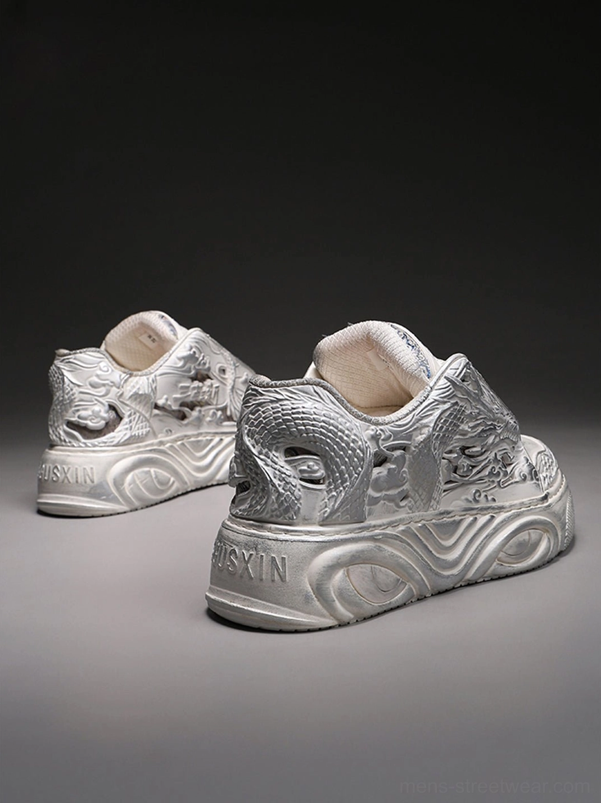 Back three-quarter view of white dragon relief platform sneakers showing textured heel panels and a wavy platform outsole