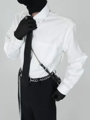 White dress shirt with textured black necktie and metallic collar pin detail styled with black gloves and silver chain accessories