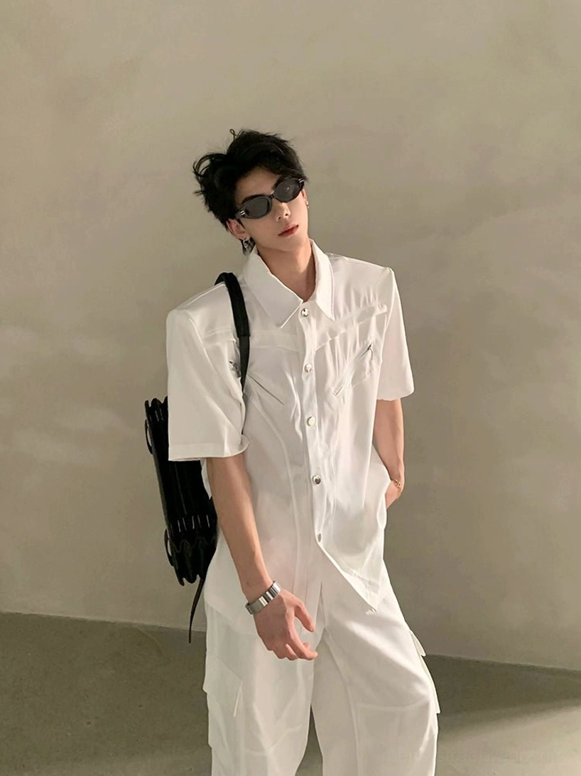 White oversized short sleeve utility shirt with pointed collar, structured shoulders, chest zipper detail, sunglasses, white cargo pants, and black backpack