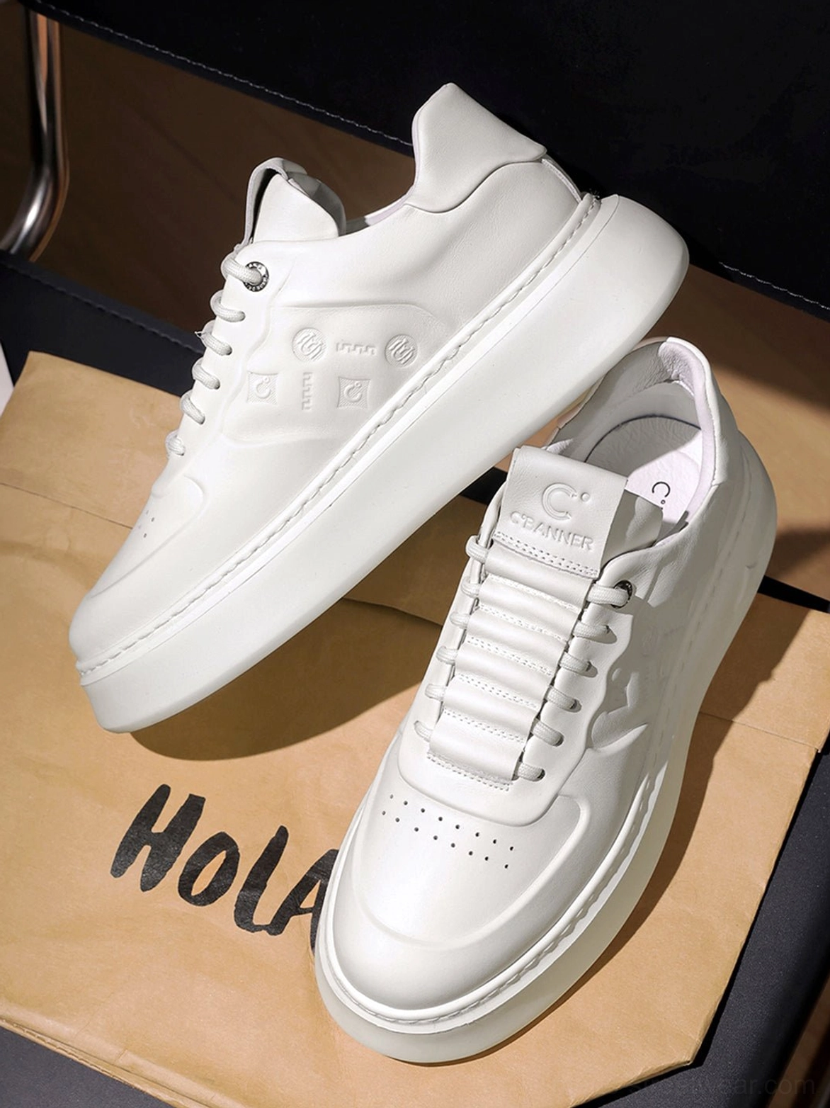 Angled overhead view of white embossed synthetic leather chunky platform sneakers with tonal textured upper