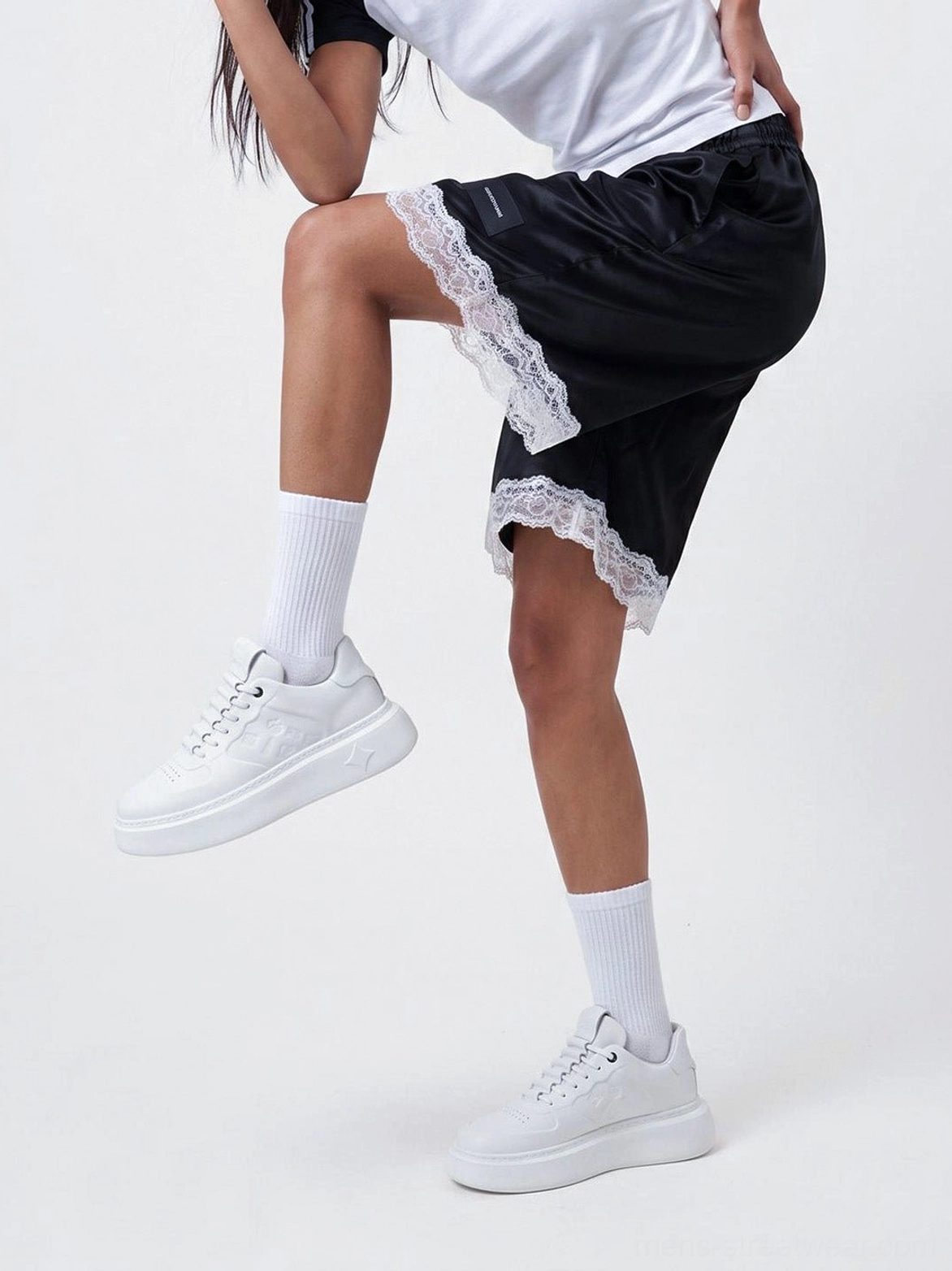 Low side angle of white embossed monogram chunky platform sneakers styled with casual streetwear clothing