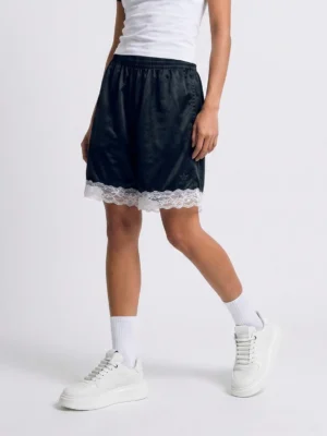 Model wearing white embossed monogram chunky platform streetwear sneakers with white crew socks and black shorts