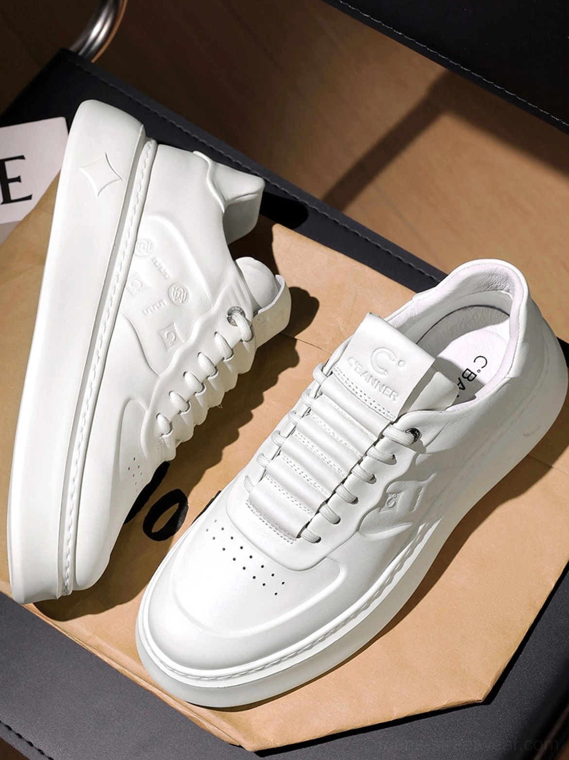 Overhead flat lay of white embossed monogram chunky platform sneakers showing perforated toe box and lace-up design