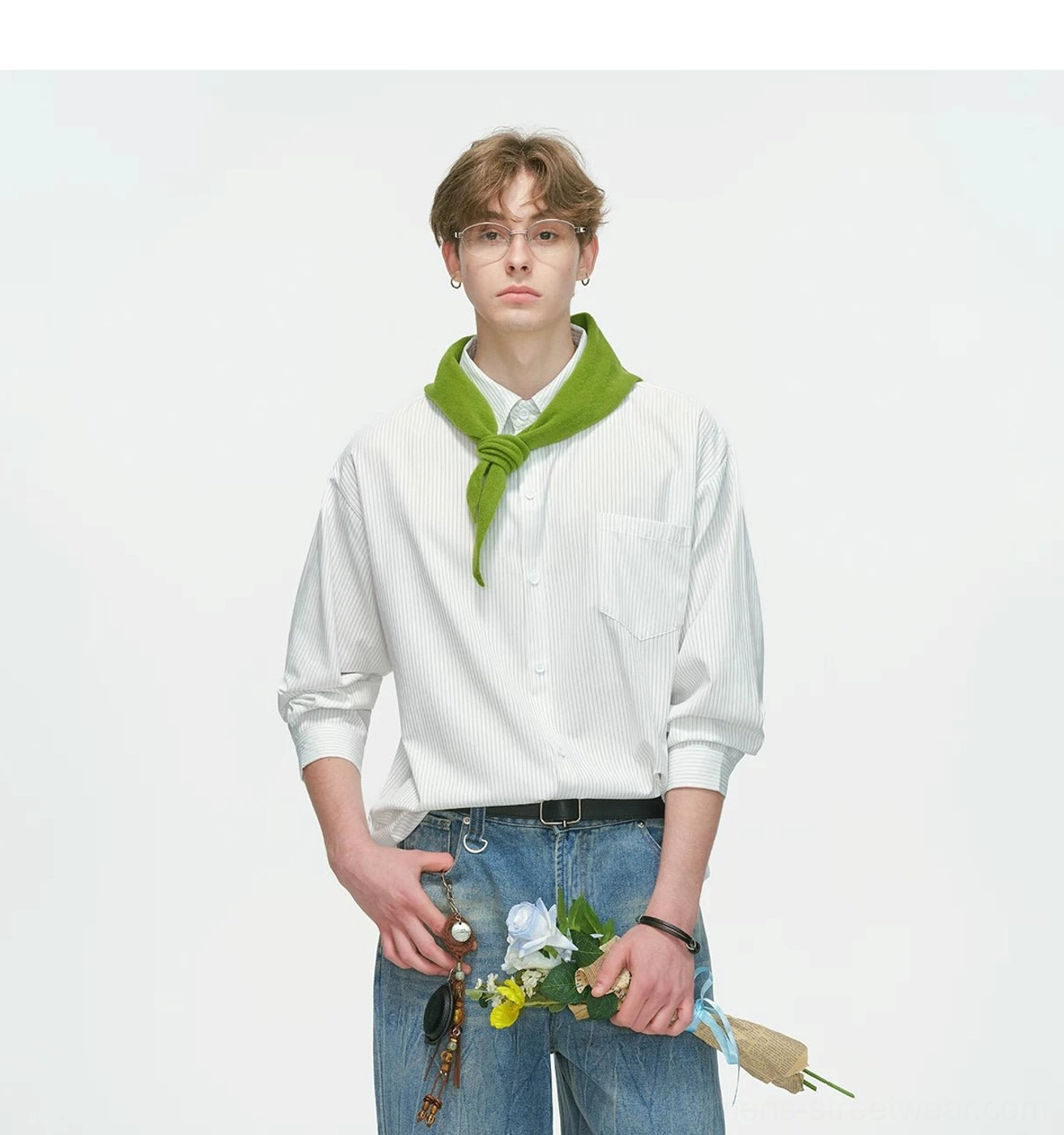 White fine stripe relaxed overshirt worn with rolled sleeves, wide-leg blue jeans, green neck scarf, flower bouquet, and black bracelet