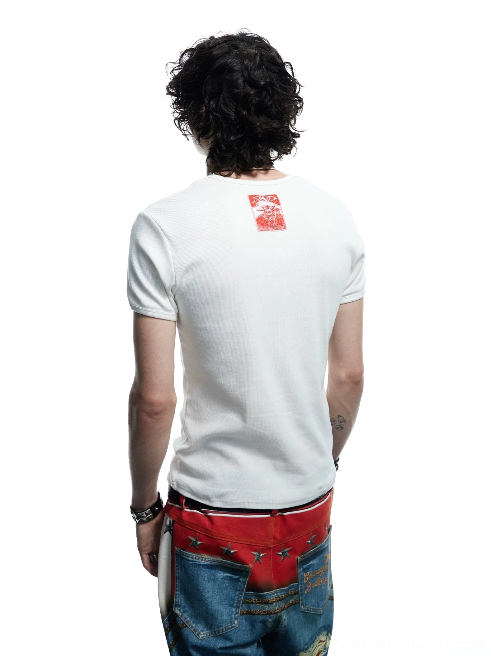 Back view of white slim-fit flaming skull baby tee showing clean rear panel and red printed tag detail with streetwear denim styling