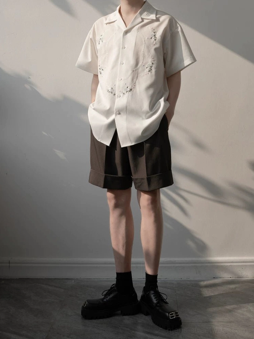 White floral embroidered short sleeve camp shirt styled with brown shorts, black dress socks, and leather loafers