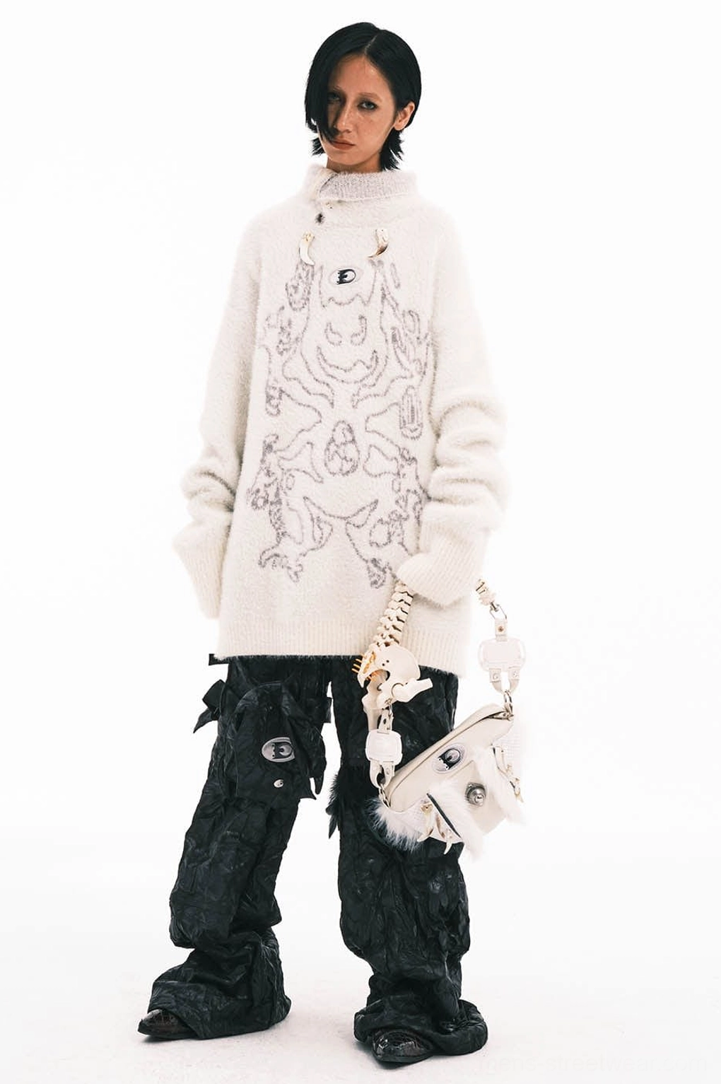 White faux bone handle fur bag styled at hip with graphic sweater and black cargo pants streetwear outfit