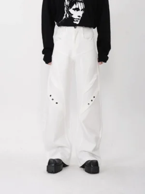 White geometric panel trousers with high waist, relaxed wide legs, industrial thigh rivets, black graphic cropped sweatshirt, and chunky sneakers