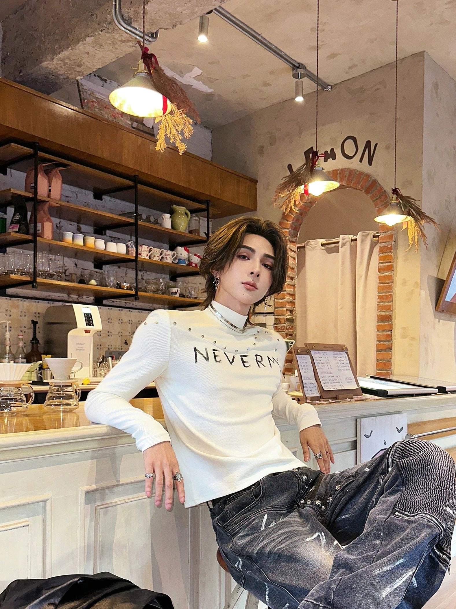 White gothic knit turtleneck sweater with slim fit, distressed chest lettering, and subtle stud details styled with distressed denim