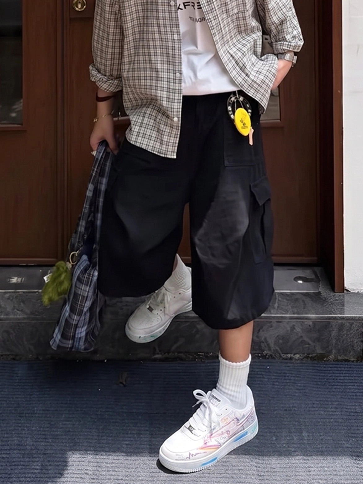 White graffiti low-top court sneakers styled with a plaid shirt and baggy cargo shorts in a casual Seoul-inspired streetwear look