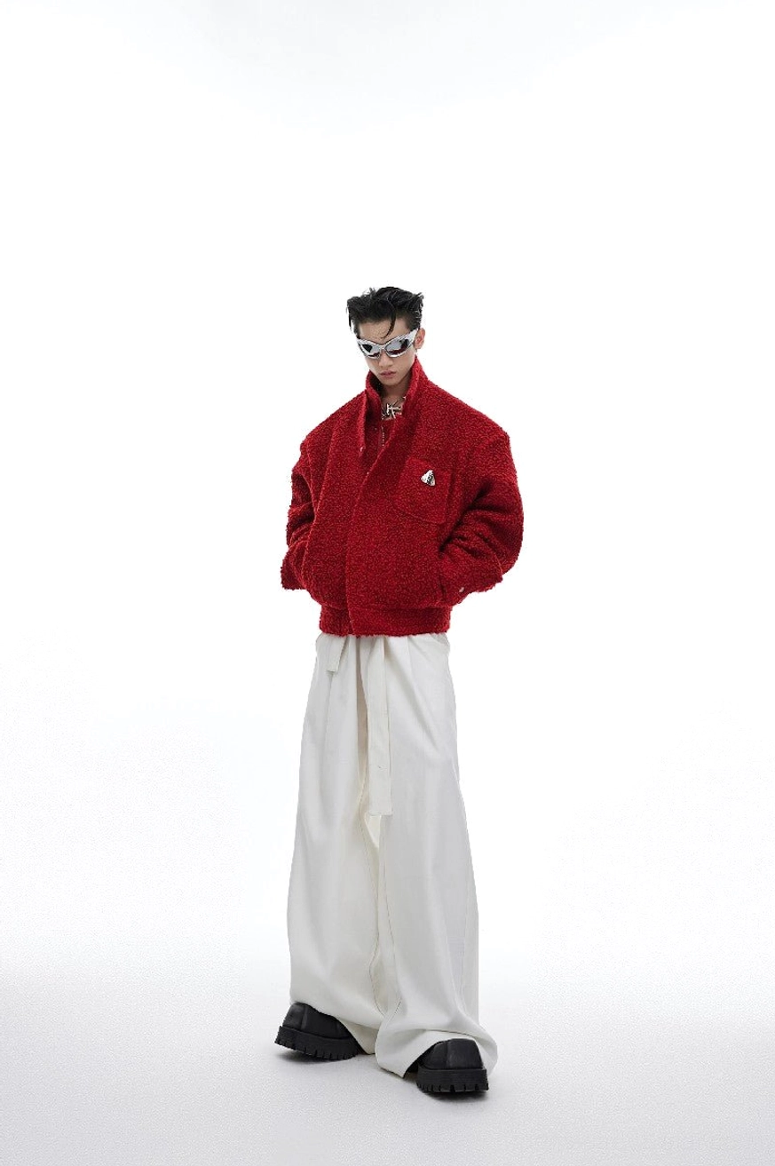 White high-waist belted wide-leg trousers styled with red cropped jacket and chunky platform shoes in minimalist studio