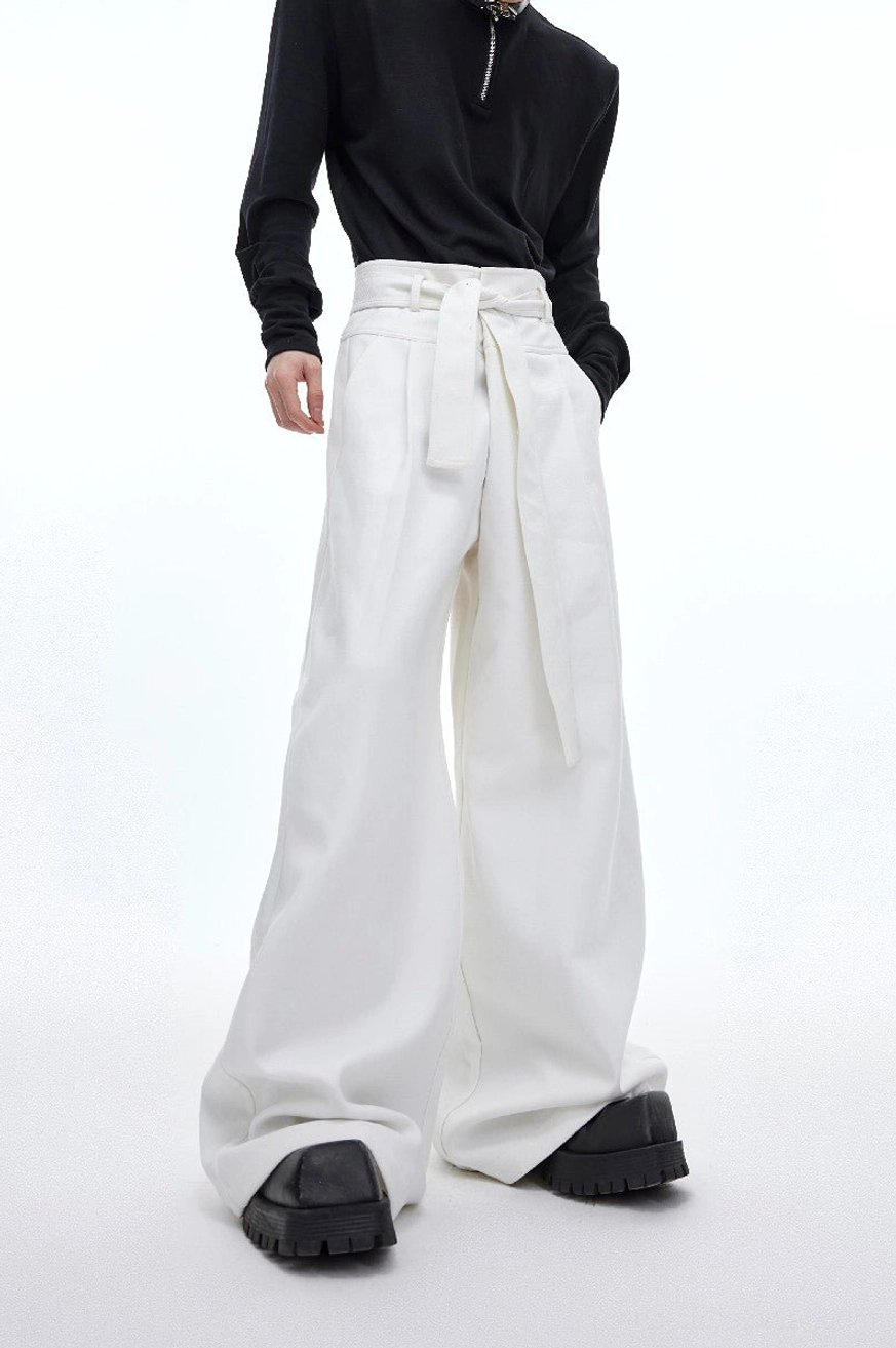 White high-waist draped wide-leg streetwear trousers with integrated waist sash styled with black top and platform boots