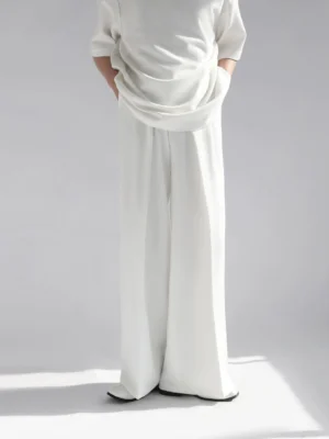 White high-waist wide leg tailored trousers front full body view in minimalist gray studio