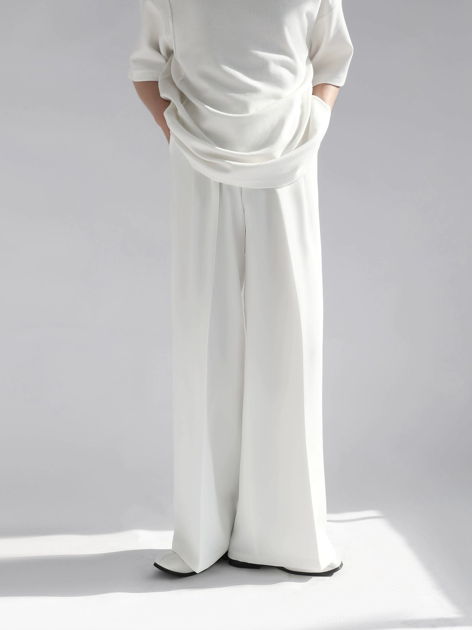 White high-waist wide leg tailored trousers front full body view in minimalist gray studio