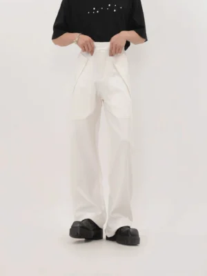 White high-waisted wide-leg panel trousers styled with a black short-sleeve tee and chunky black leather shoes in a studio streetwear outfit