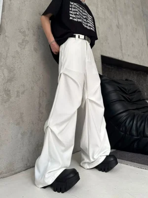 White high waisted wide leg pleated trousers styled with a black slogan tee and chunky footwear in a low rear side streetwear view