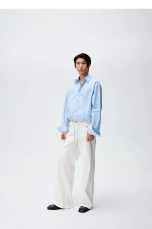 Front view of white high-waisted wide-leg sailor trousers with adjustable waist styled with a light blue button-down shirt and black loafers