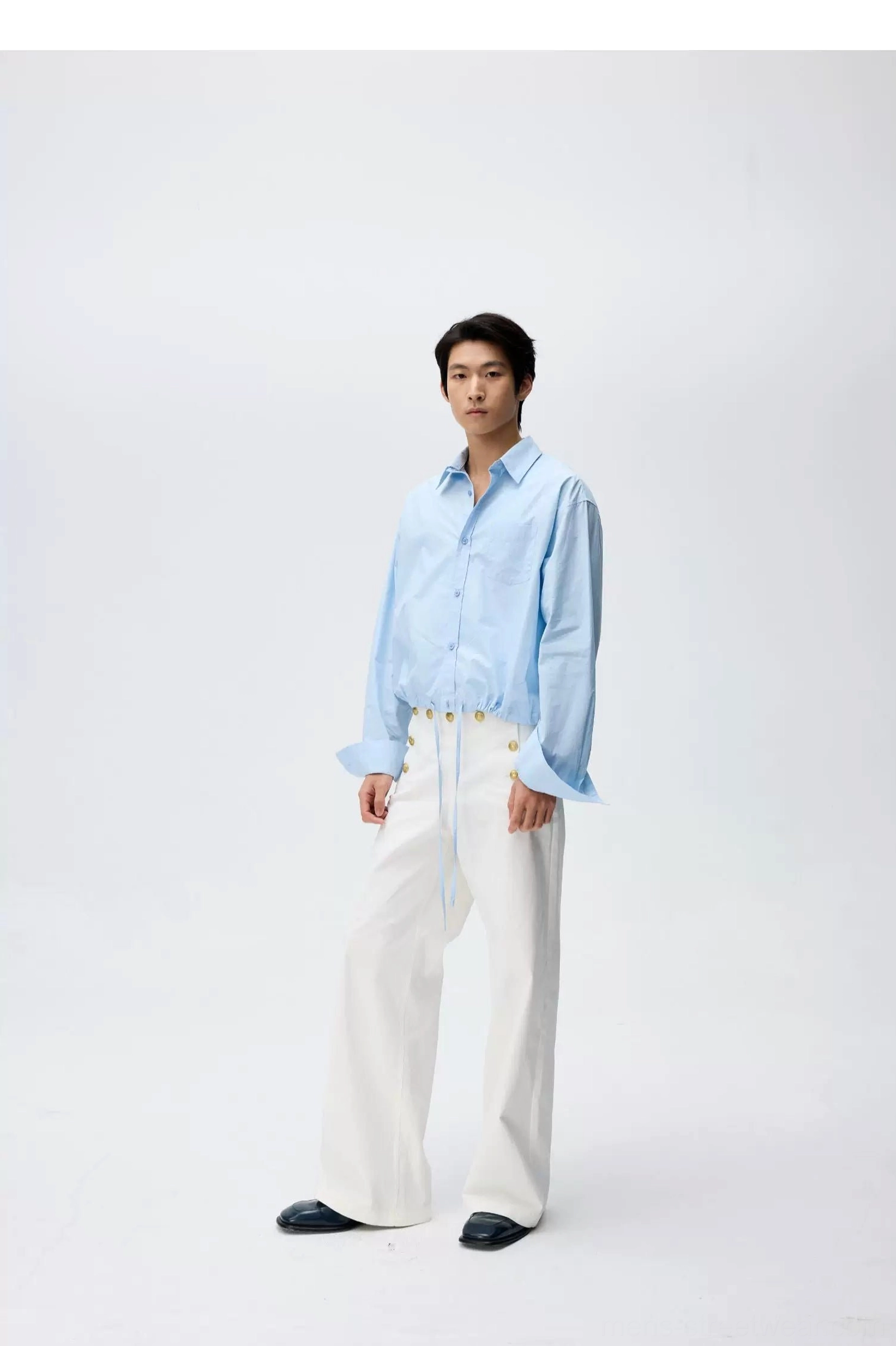 Front view of white high-waisted wide-leg sailor trousers with adjustable waist styled with a light blue button-down shirt and black loafers