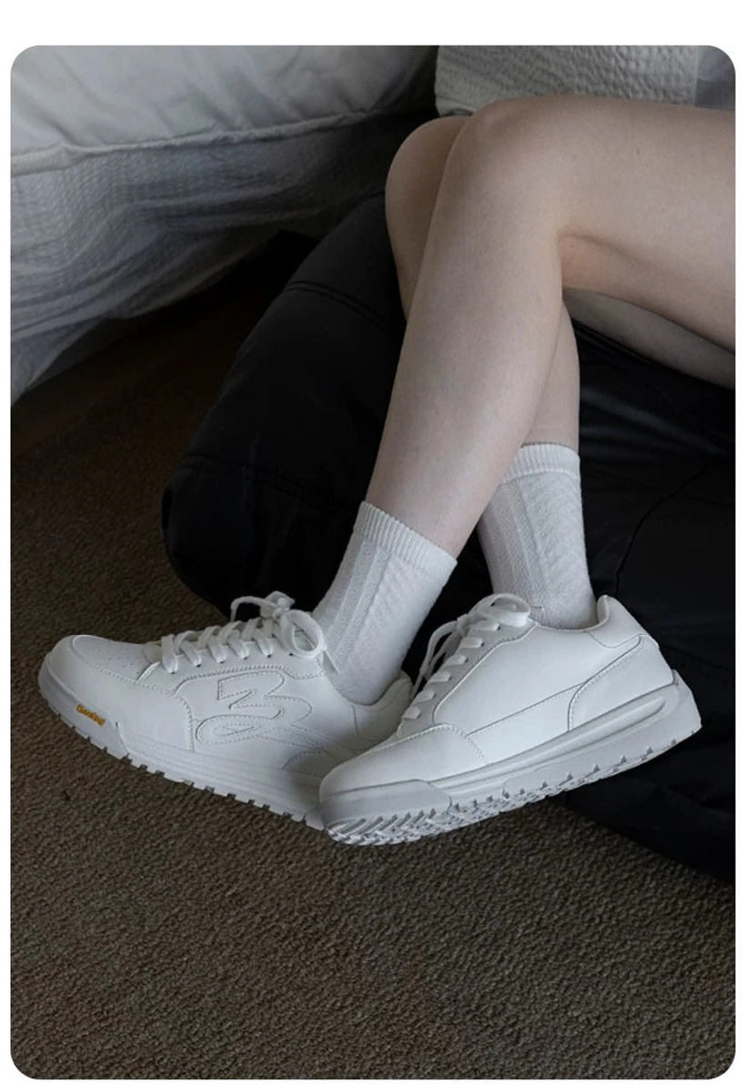 White low-top flame detail platform skate sneakers worn indoors showing textured rubber outsole and side profile