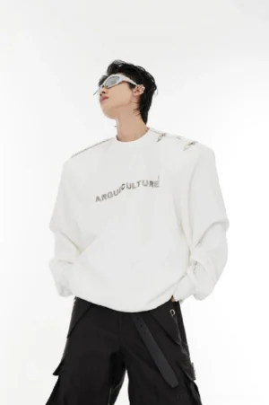 White oversized streetwear sweater with metallic chest logo, shoulder buckles, and futuristic techwear details styled with black cargo pants