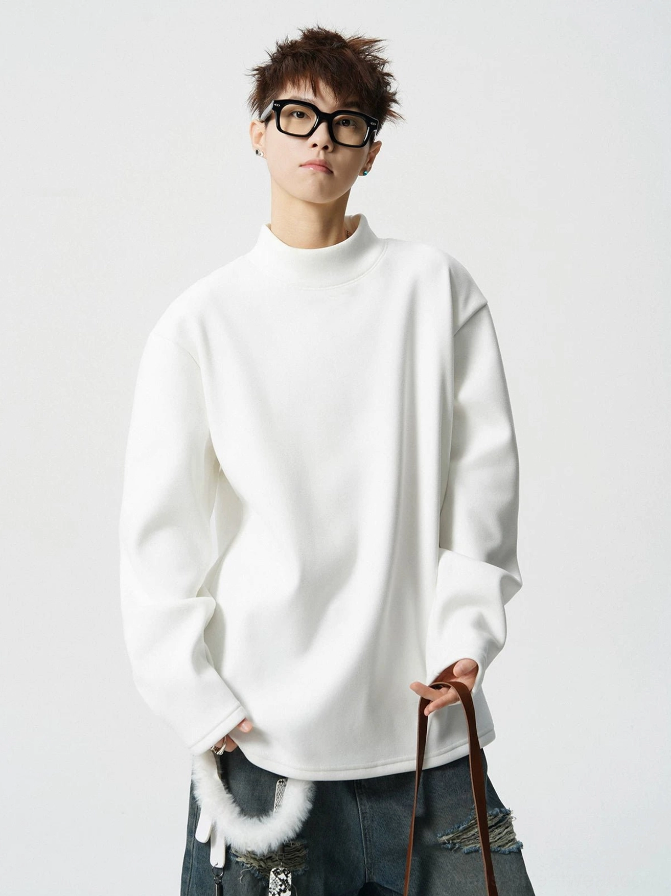White minimalist mock neck fleece pullover top styled with baggy jeans and thick black frame glasses