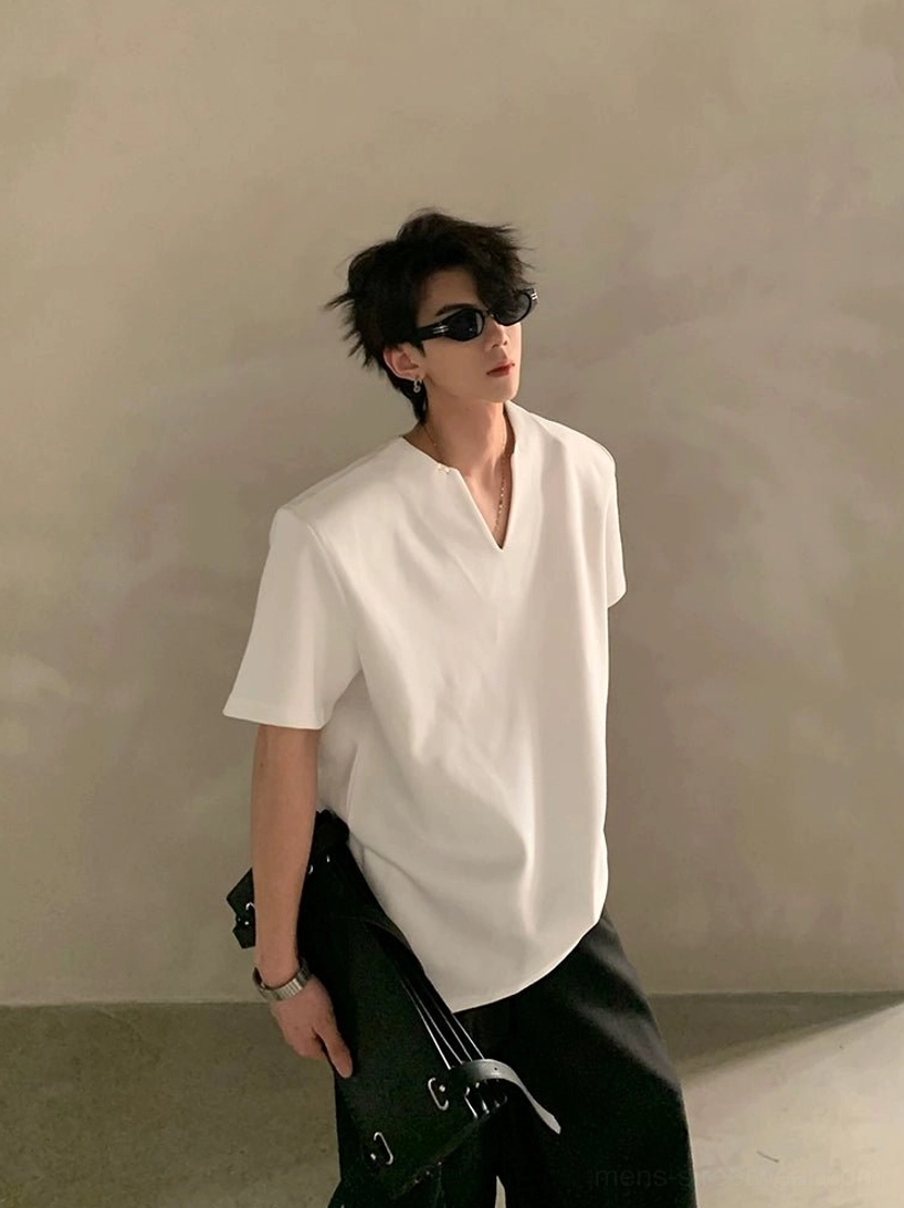 Male model wearing a white minimalist V-notch neck shirt with wide-leg black trousers and a handheld bag in clean Asian streetwear styling