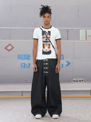 White graphic ringer tee with vertical NERD portrait print styled with wide-leg black denim, metal details, and crossbody bag