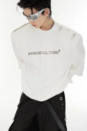 White oversized crewneck sweater close-up showing silver metallic logo, shoulder hardware, and Korean streetwear styling