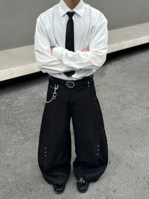 Full-length male model wearing a crisp white oversized dress shirt with black tie, wide-leg trousers, leather shoes, belt, and chain in a Seoul-inspired streetwear look