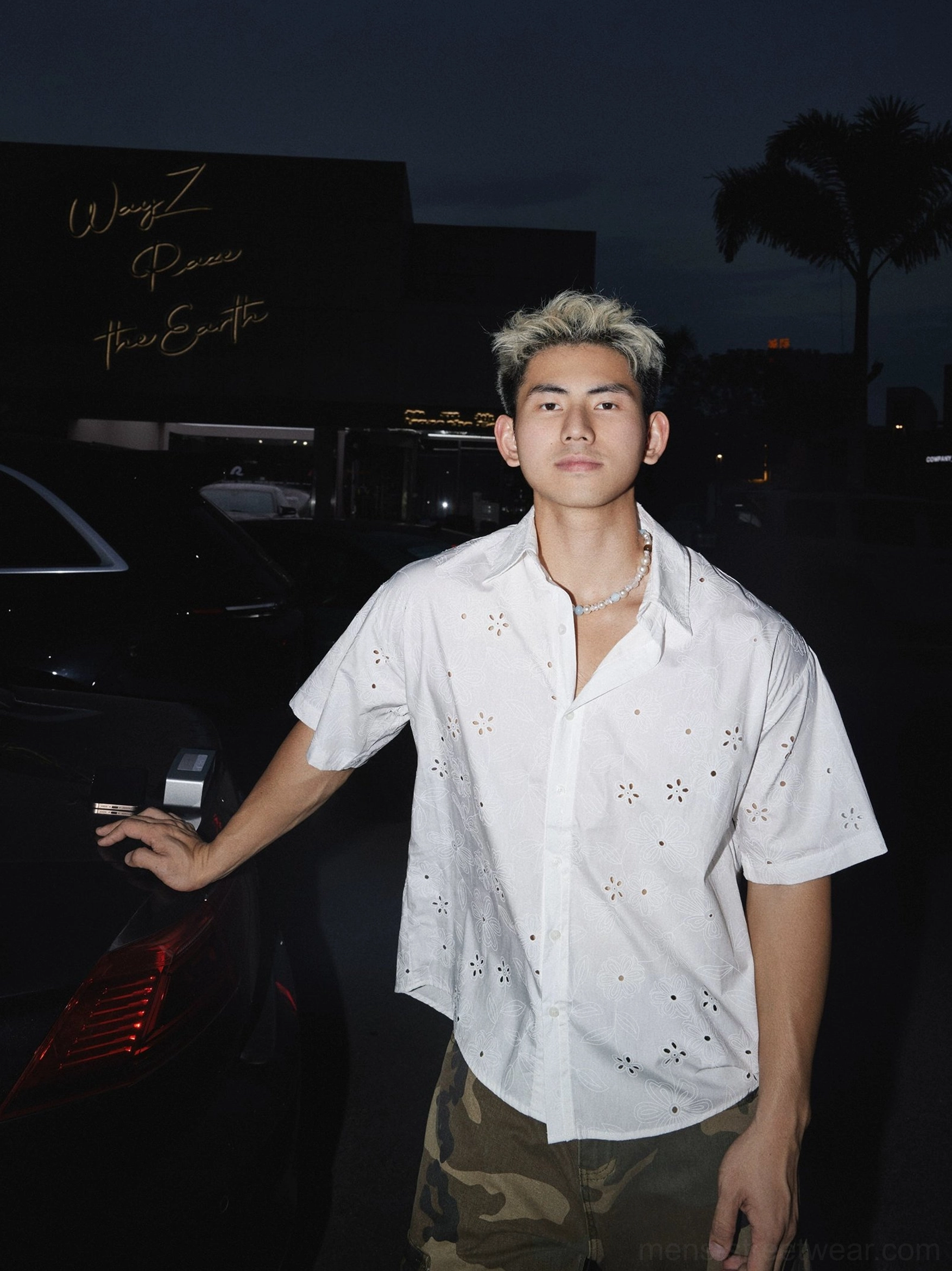 White oversized floral eyelet short sleeve shirt worn with camouflage cargo pants in an urban streetwear outfit