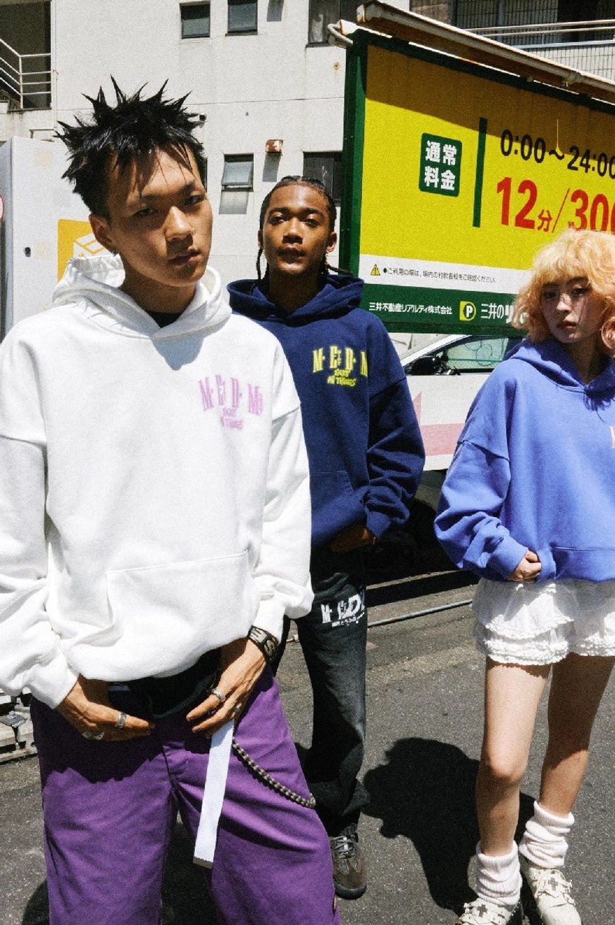 White oversized graphic hoodie with pink chest print, front kangaroo pocket, loose streetwear fit, and urban layered styling