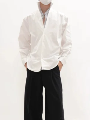 White oversized longline button-up shirt with raised collar styled with black wide-leg trousers in minimalist Korean streetwear look