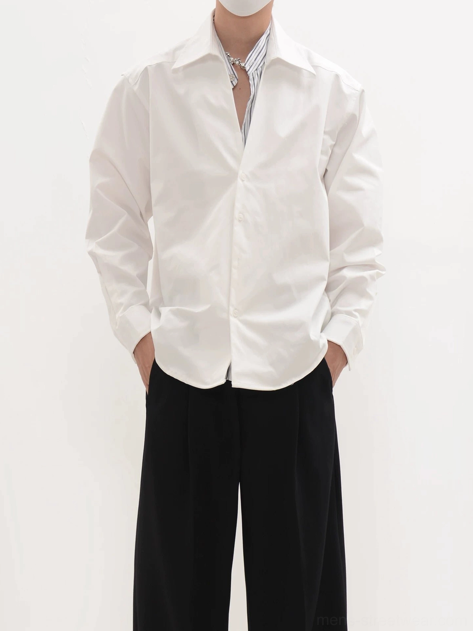 White oversized minimalist shirt layered over striped inner top with black wide-leg pants Seoul fashion styling