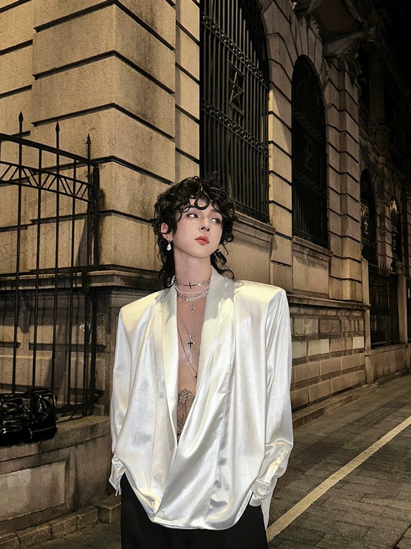 White oversized satin deep V-neck shirt with smooth finish styled against a vintage stone building
