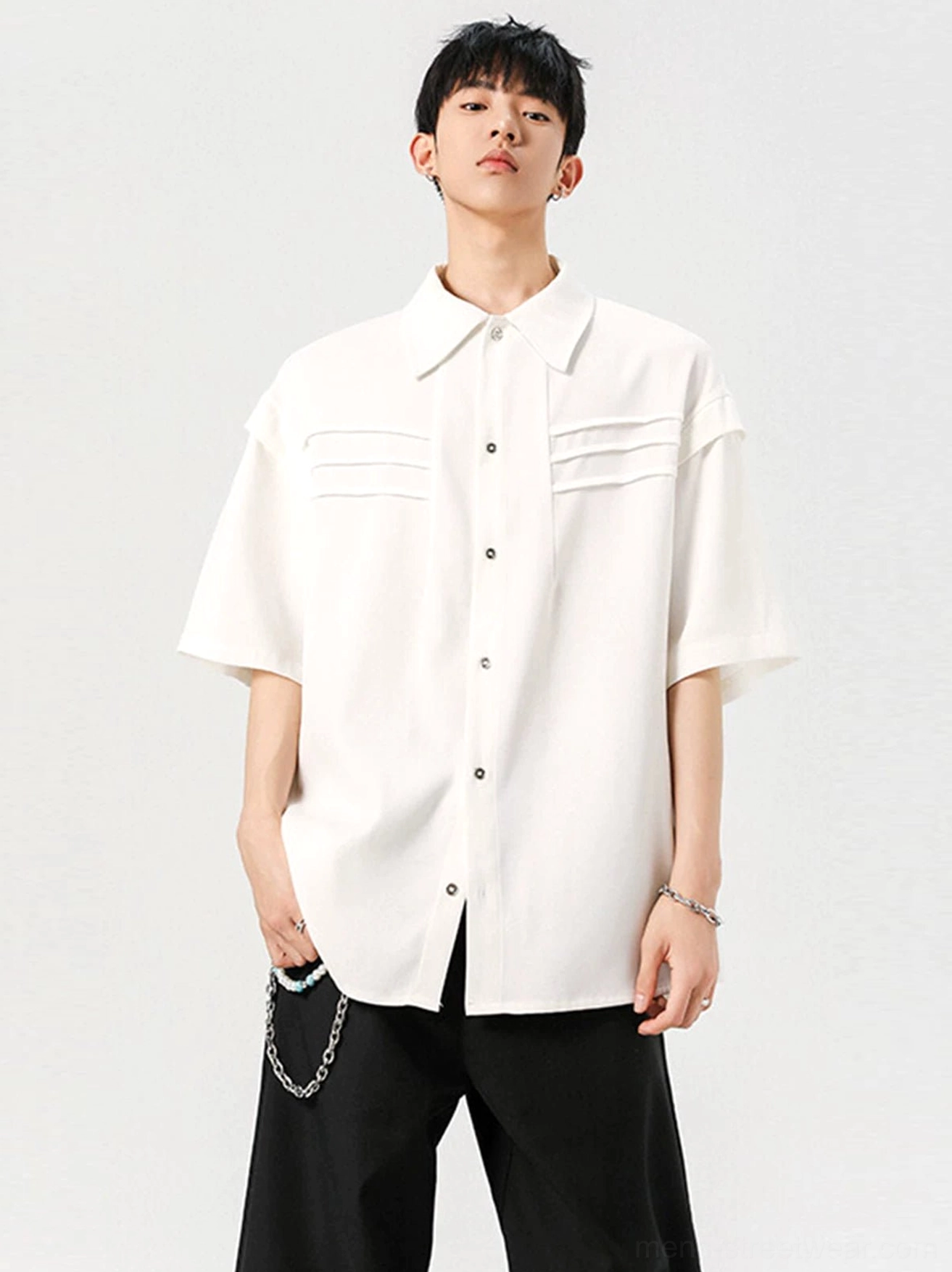 White oversized short sleeve streetwear shirt shown from a front three-quarter angle with pleated chest details and polished buttons