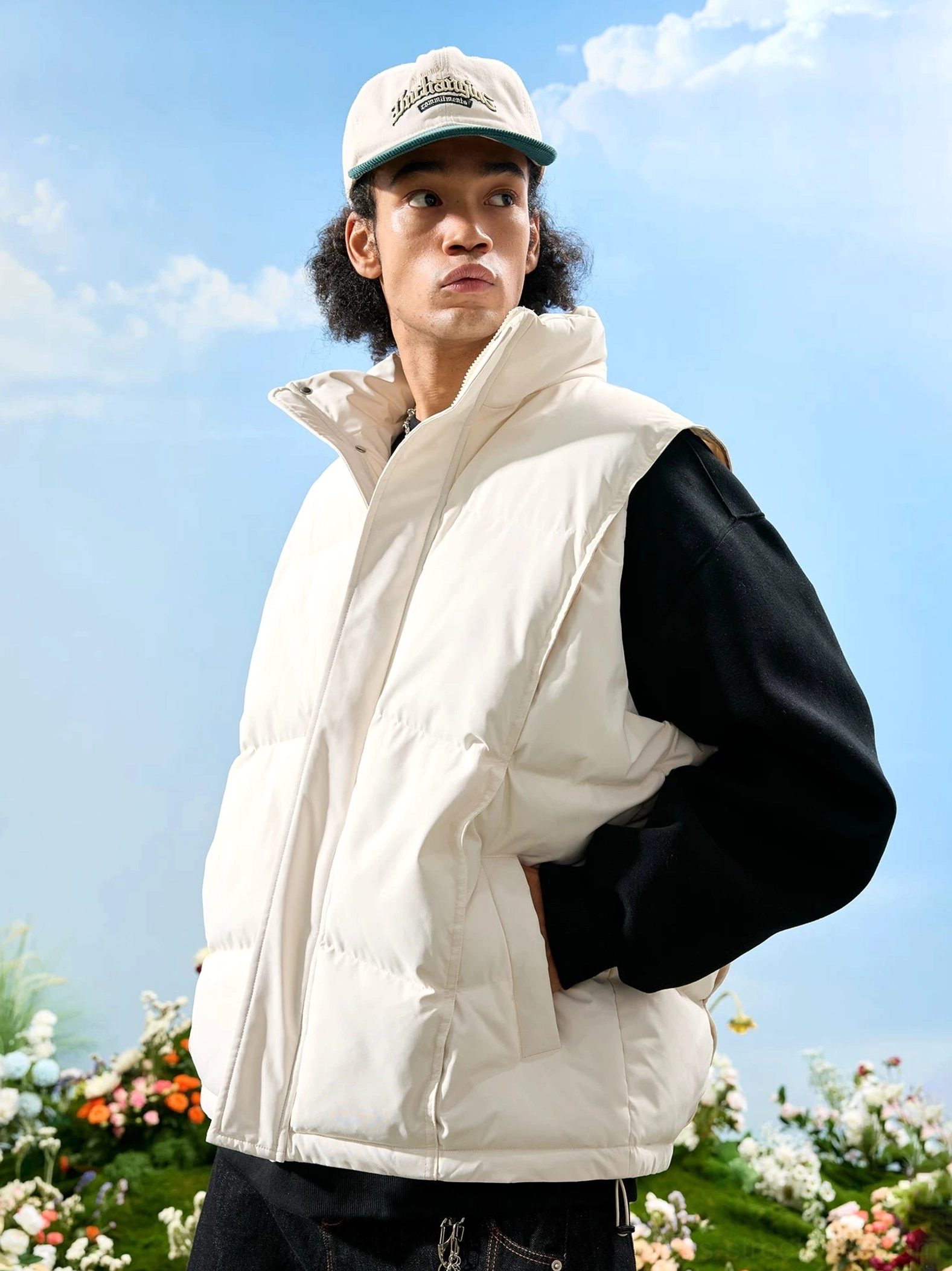 White oversized stand collar puffer vest with quilted padded panels layered over a black long sleeve top