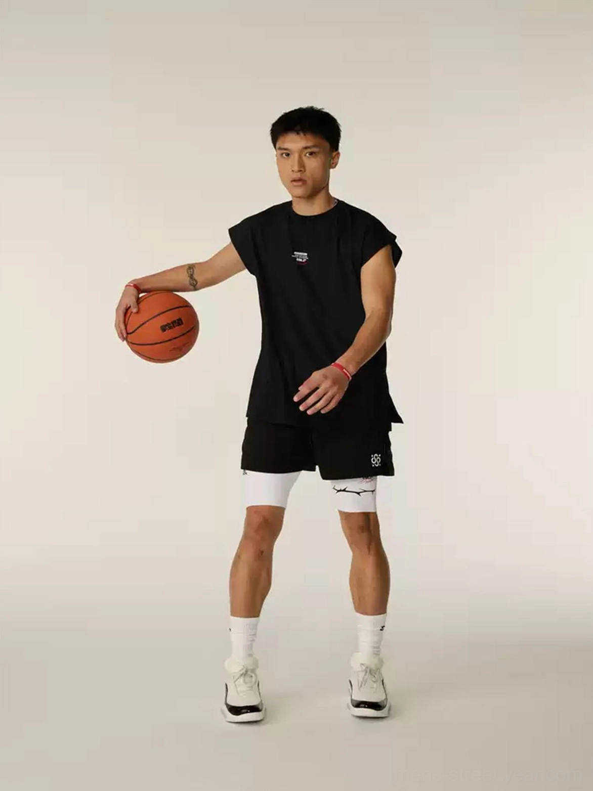 Basketball player wearing white PEBAX leather performance sneakers with black sportswear and holding an orange basketball