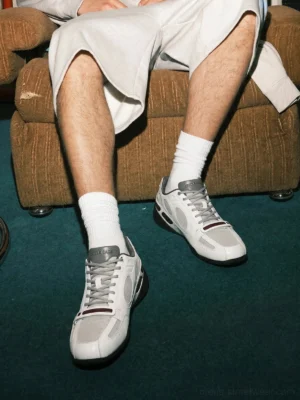 Male model wearing white perforated retro sport sneakers with white crew socks in a relaxed streetwear setting