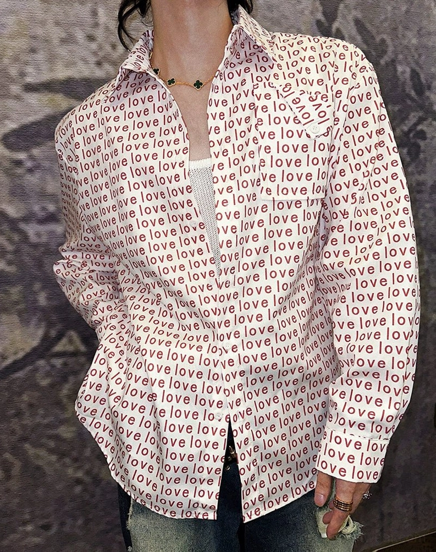 Close-up front product view of white button-up shirt with repeating red love text print and chest pocket