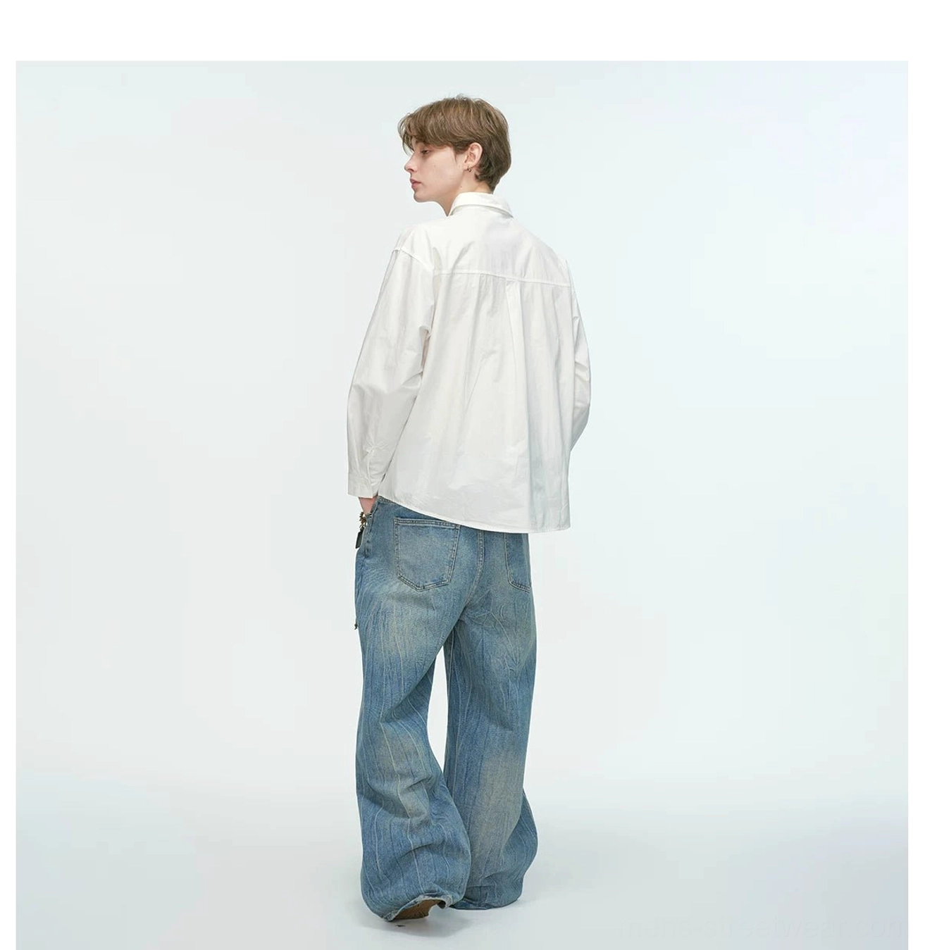 Back view of a white relaxed poplin shirt showing its clean oversized silhouette with wide-leg blue denim
