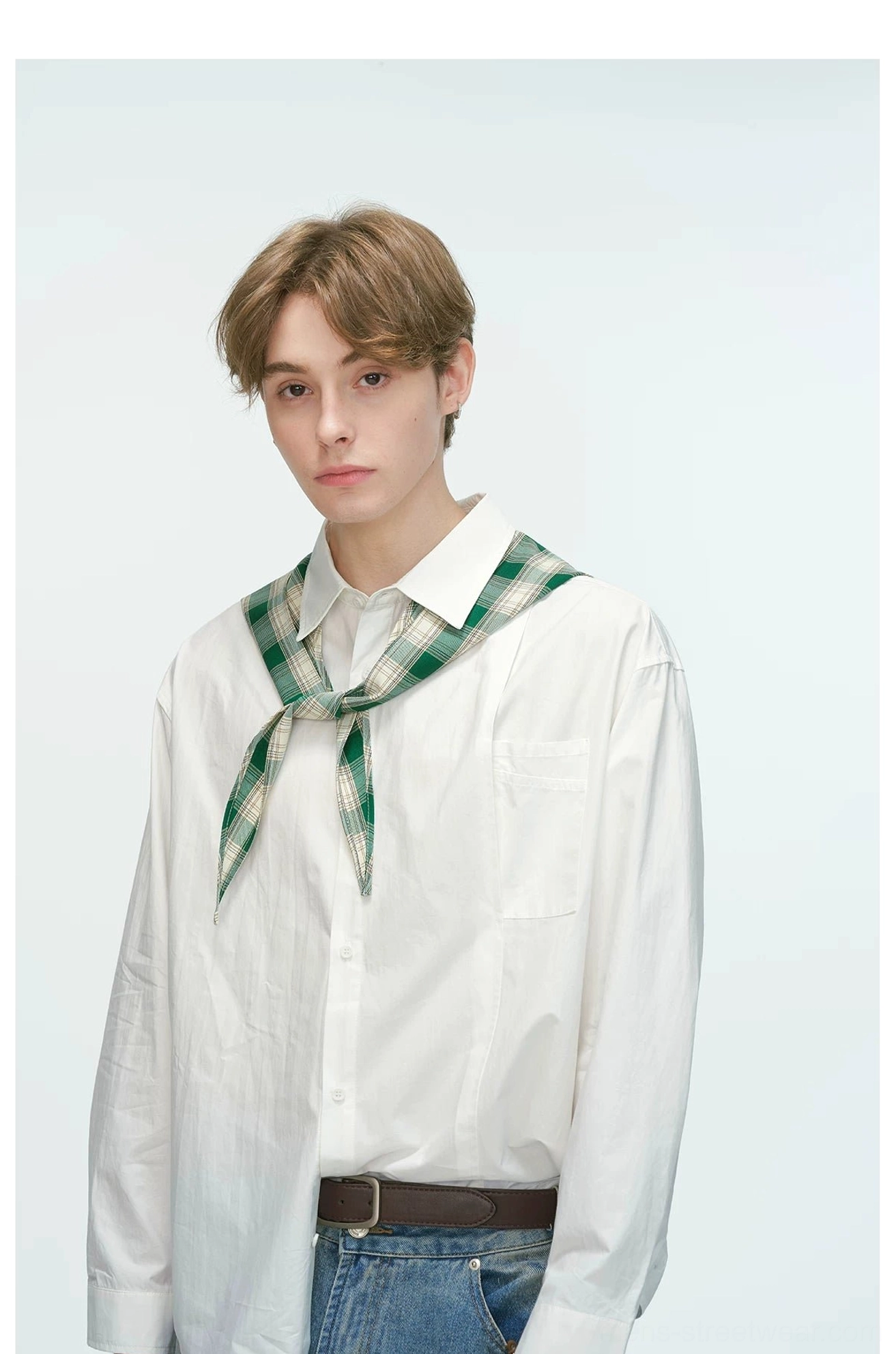 Close-up view of a white relaxed poplin shirt showing pointed collar chest pocket and green plaid neckerchief styling