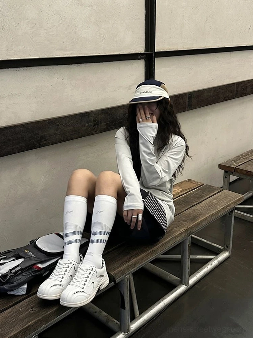 White casual retro runner sneakers styled with shorts, knee-high striped socks, and a relaxed Korean-inspired streetwear outfit