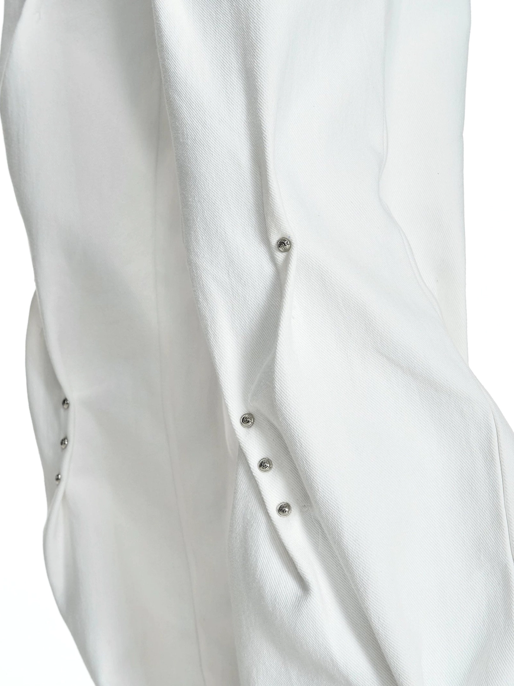 Close-up of white cotton denim pants with textured fabric sculpted folds curved seams and decorative metal rivets